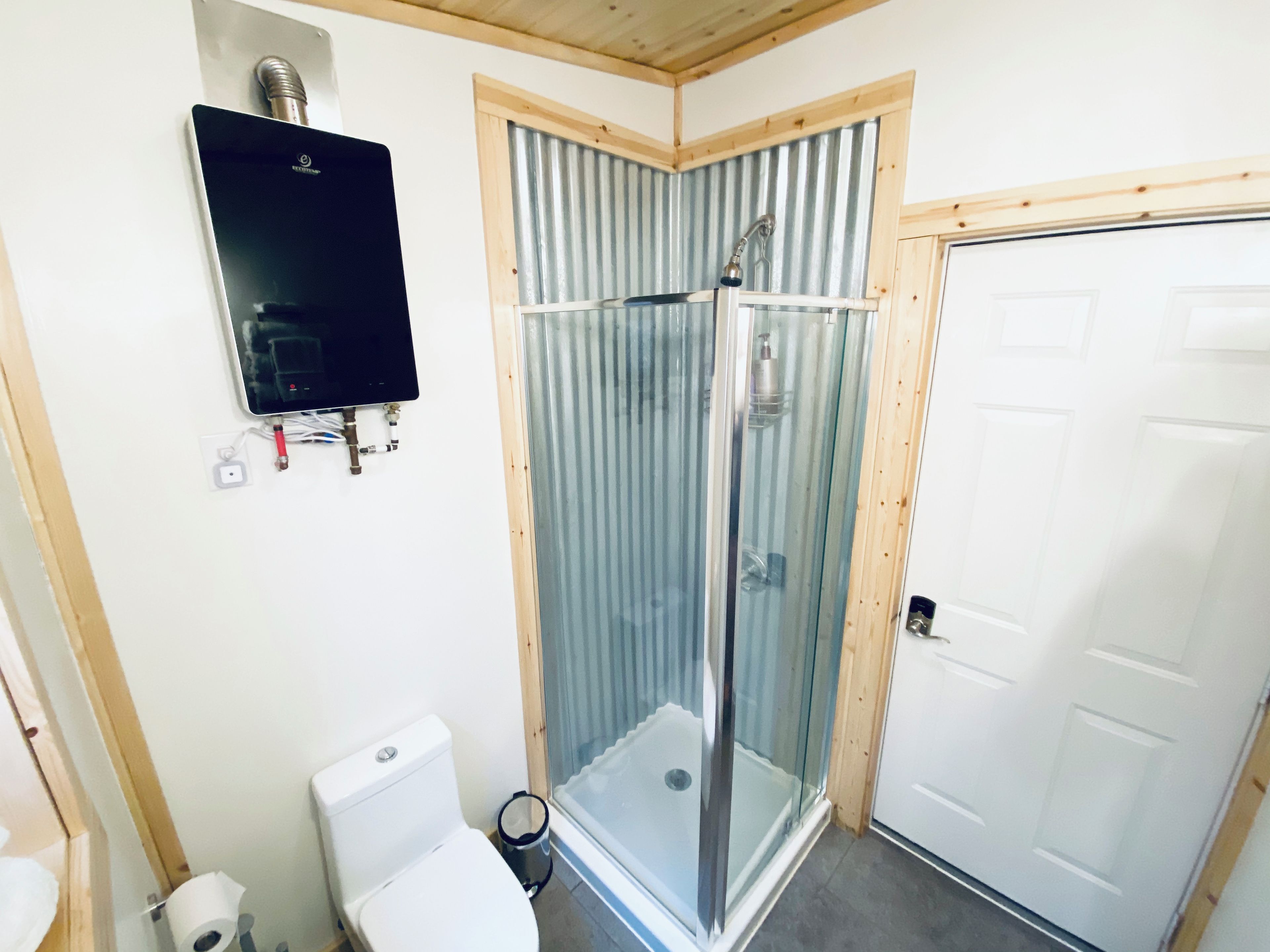 Un baño con inodoro, cabina de ducha y puerta blanca.