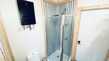 Un baño con inodoro, cabina de ducha y puerta blanca.