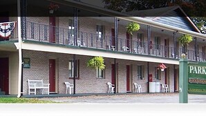 A two-story motel with a balcony on the upper floor, a sign indicating it's the Park-Lake Motel, and a view of the entrance to Letchworth Park & Silver Lake. - Park Lake Motel (Perry)