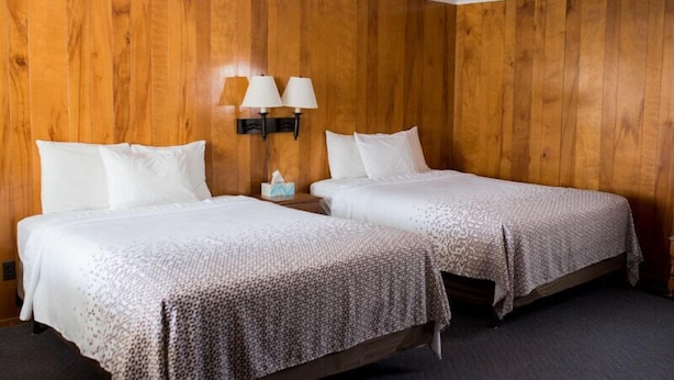 A hotel room with two beds, wooden panel walls, and two wall-mounted lamps. - Park Lake Motel (Perry)