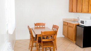 A compact kitchen with a wooden table and chairs, a microwave, and a refrigerator. - Park Lake Motel (Perry)