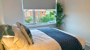 A bedroom with a bed, a lamp, a window, and a plant. - Consett Shotley Bridge, Stylish & Modern Two Bedroom Apartment (Consett)