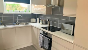 A compact kitchen with a sink, toaster, kettle, and a black induction cooktop. - Consett Shotley Bridge, Stylish & Modern Two Bedroom Apartment (Consett)