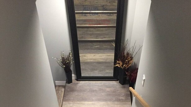 A wooden staircase with a handrail, leading to a door with a welcome sign. - The Cedar Suite (Yellowhead County)