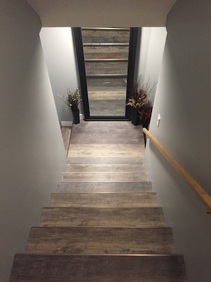 Eine Holztreppe mit Handlauf, die zu einer Tür mit einem Willkommensschild führt.