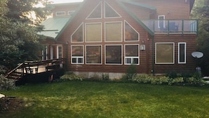 A two-story wooden house with a prominent gable roof and large windows. - The Cedar Suite (Yellowhead County)