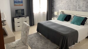 Ein modernes Hotelzimmer mit einem großen Bett, einem Schreibtisch mit Computer, einem Sessel und einem Bild an der Wand.