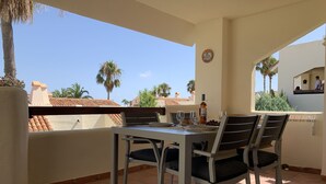 Eine Terrasse mit Tisch und Stühlen, einer Weinflasche und einer Schale Trauben.