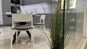 Eine moderne Küche mit weißen Stühlen, einem Esstisch und einem Blumentopf.