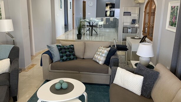 Ein modernes Wohnzimmer mit einer Couch, einem Couchtisch und einem Essbereich im Hintergrund.