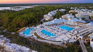 A resort with multiple swimming pools, a covered outdoor area, and a view of the surrounding forest and water. - Camp District | Access to WaterColor Amenities (Santa Rosa Beach)