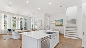 A spacious kitchen with a large island, white cabinetry, and a wooden staircase. - Camp District | Access to WaterColor Amenities (Santa Rosa Beach)