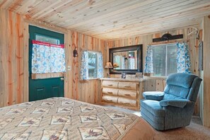A wooden cabin bedroom with a bed, dresser, chair, and a mirror. - STUNNING ROCKY MOUNTAIN VIEWS!!!!! (Estes Park)