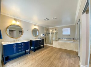 A modern bathroom with two sinks, a walk-in shower, and a large bathtub.