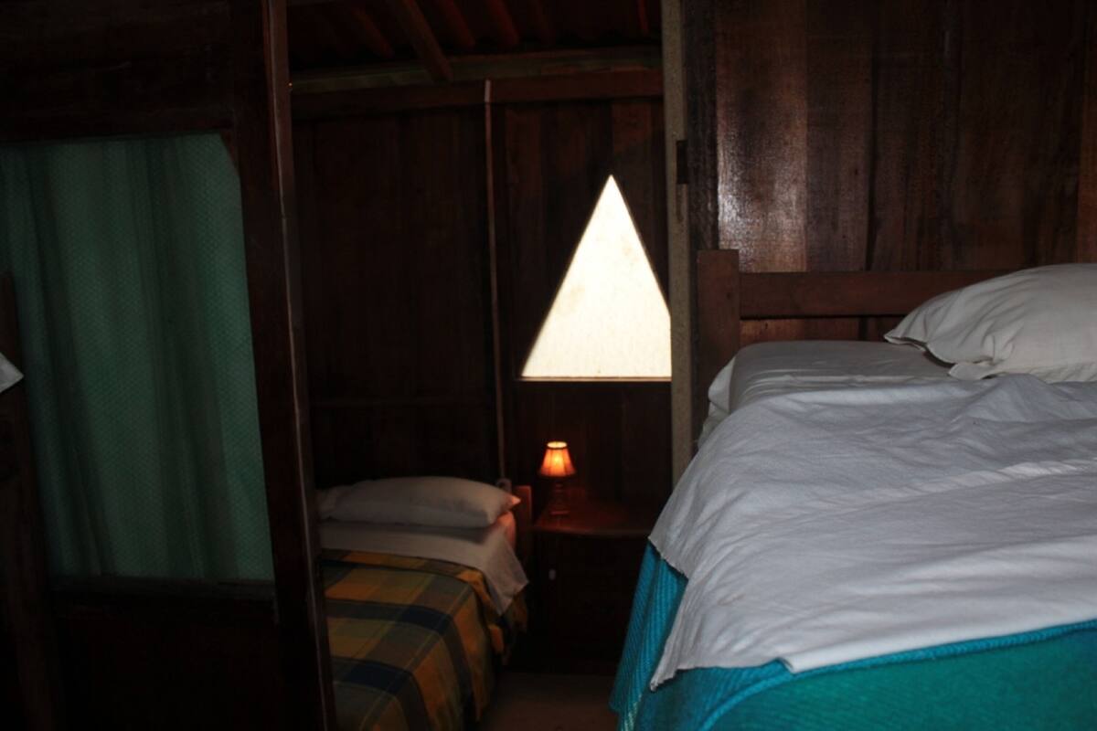 A room with a bed, a nightstand with a lamp, and a window with curtains.