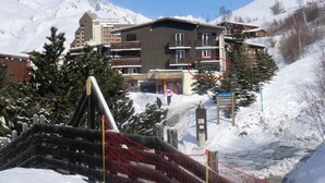 Un hotel de varios pisos, un telesilla al fondo y un paisaje montañoso nevado.