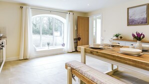 A dining area with a wooden table, bench, and a view of the outdoors through a large window.