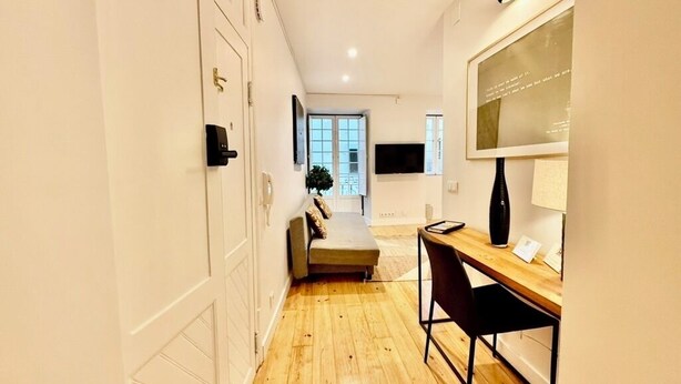 En hall med trägolv, ett skrivbord med en stol, en soffa och en dörr med ett lås.