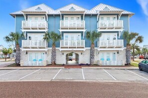 Un hotel de varios pisos con balcones, una entrada principal y un estacionamiento.