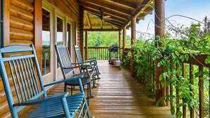 A wooden porch with a covered seating area, a ceiling fan, and a view of the surrounding greenery. - Drive in Theater! Putt-Putt | Fire Pit | Top 10% (Sevierville)