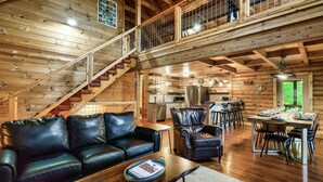 A spacious wooden cabin interior with a living area, dining table, and kitchen. - Drive in Theater! Putt-Putt | Fire Pit | Top 10% (Sevierville)