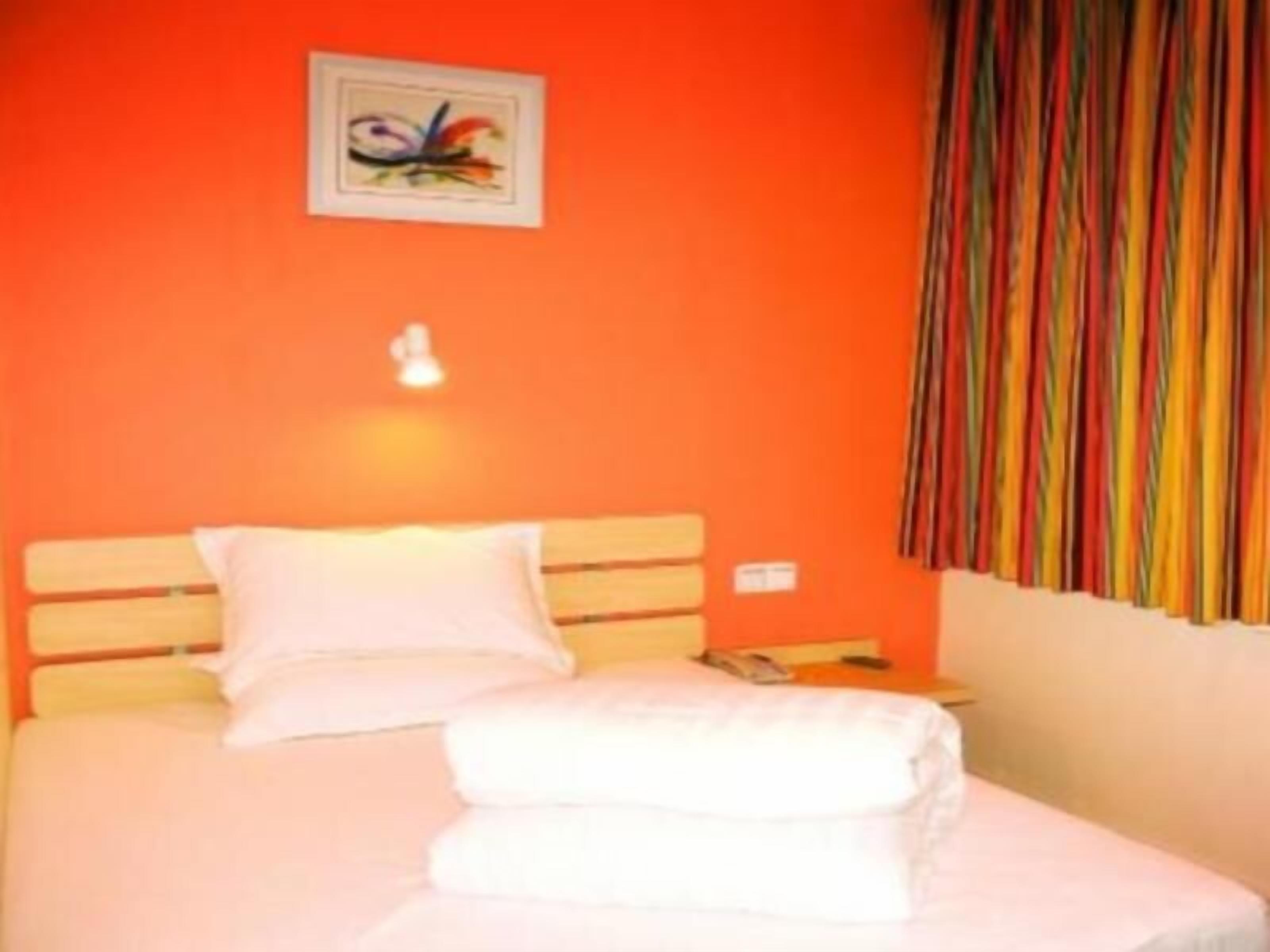 A bed with white linens, a wooden headboard, and a colorful striped curtain.