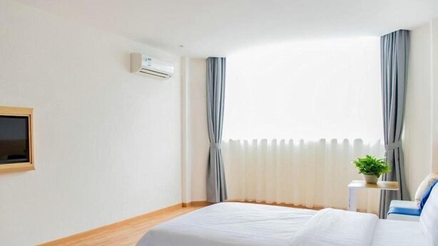 A hotel room with two beds, a TV mounted on the wall, an air conditioning unit, and a window with curtains. - 7 Days Inn Yiyang Center Branch (Yiyang)