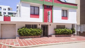 A hotel with a red and white facade, a green awning, and a satellite dish. - Ayenda 1622 Charmin (Santa Marta)