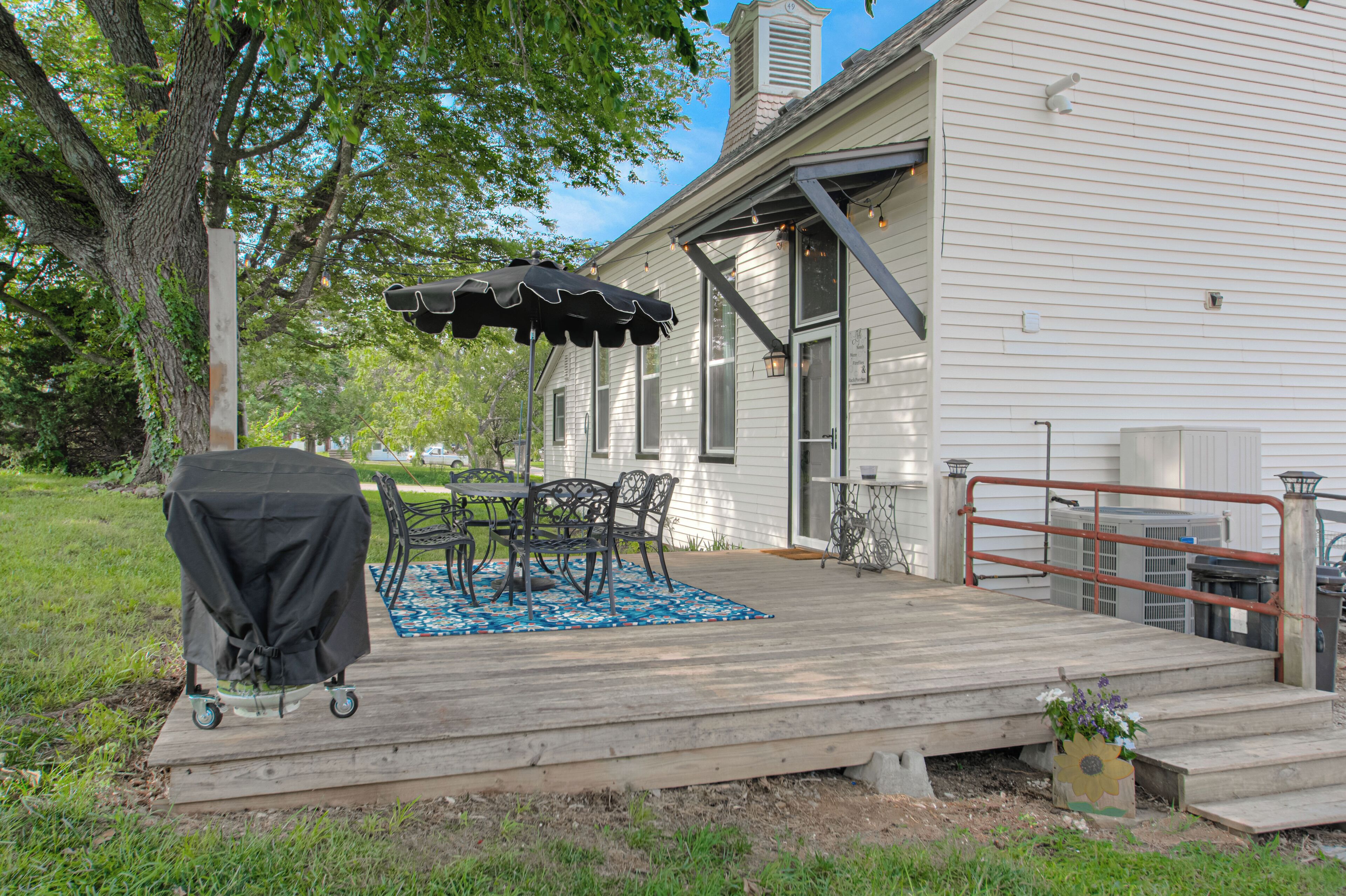 A wooden deck with outdoor furniture, a covered grill, and a small garden area.
