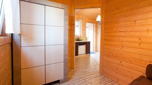 Un interior de madera con cocina, un armario y un pasillo que lleva a otra habitación.