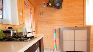 Un interior de madera con una zona de cocina que incluye una estufa, ollas y un armario.