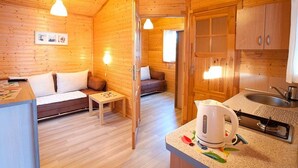 Una cabaña de madera acogedora con un sofá, una mesita y un rincón americano.