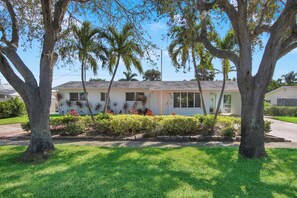 A single-story house with a front yard, surrounded by trees and a well-maintained lawn.