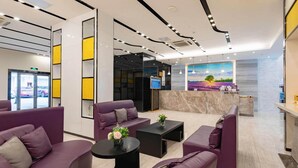 Una hall moderna con divani viola, una reception e un'ampia finestra.