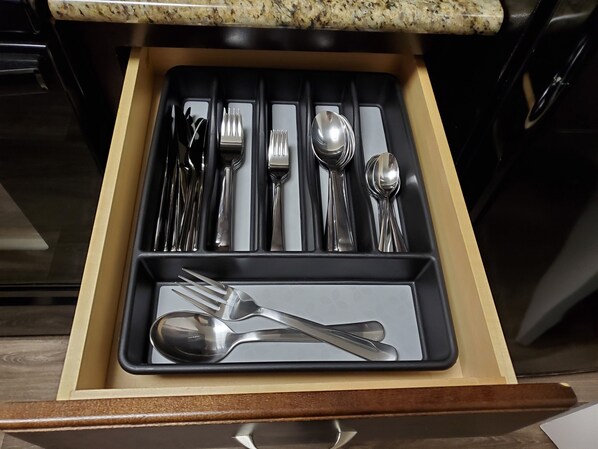 A drawer with neatly arranged cutlery including forks, knives, spoons, and a butter knife.