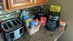 A kitchen counter with a toaster, coffee maker, and various coffee pods and containers.