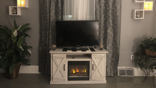 A living room with a fireplace, a flat-screen TV, and decorative lighting.
