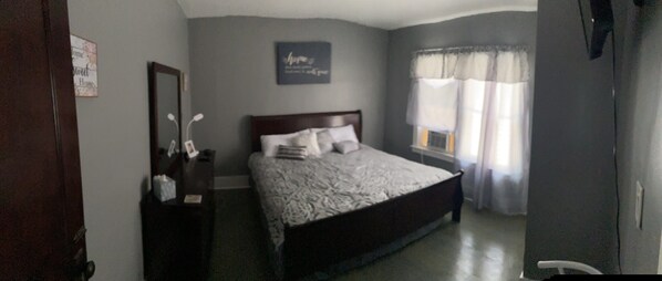 Un dormitorio con cama, cómoda, espejo y ventana con cortinas.