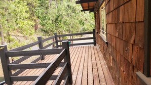 A wooden deck with a railing, surrounded by trees.