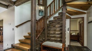 A wooden staircase with a bench at the bottom, leading to a room with a bed and a door.