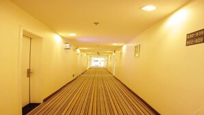 Ein Hotelgang mit Streifenmuster-Teppich, Türen auf beiden Seiten und einem Schild mit Telefonnummern.