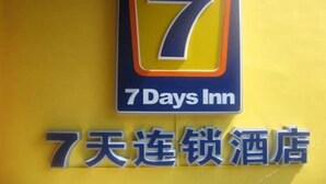 Ein Schild für 7 Days Inn mit einer gut sichtbaren Zahl 7 und dem Namen in englischer und chinesischer Schrift.
