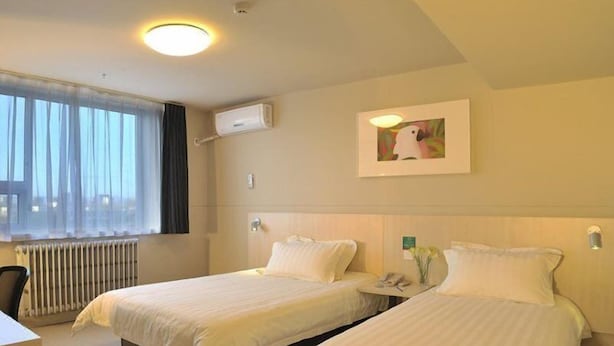 A hotel room with two beds, a desk, a chair, a radiator, and a window with sheer curtains. - Jinjiang Inn Hohhot Erdos East Street Branch (Hohhot)