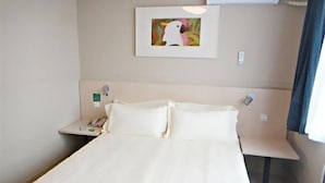 A hotel room with a bed, a nightstand, a wall-mounted air conditioner, and a framed picture. - Jinjiang Inn Hohhot Erdos East Street Branch (Hohhot)