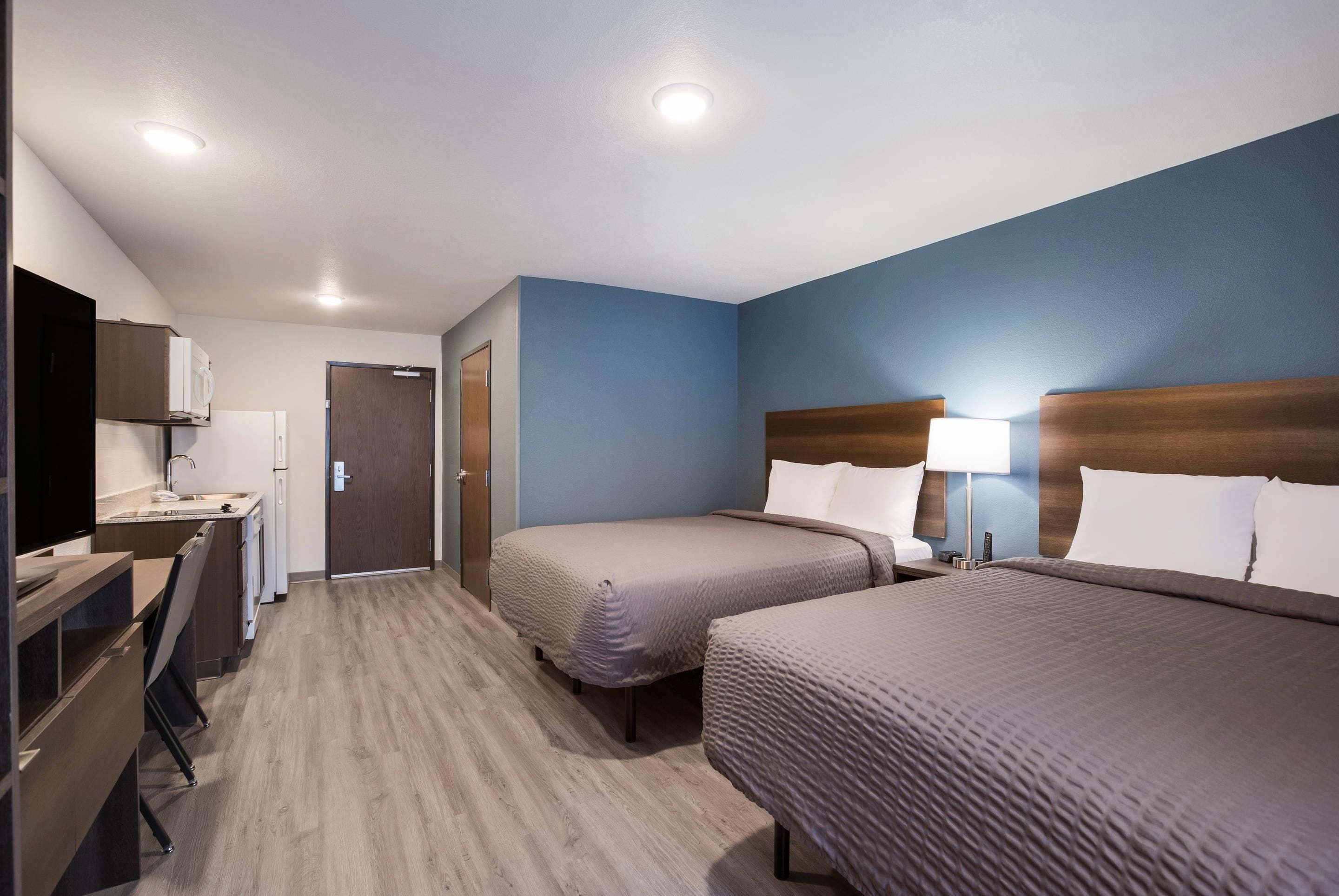 Une chambre d’hôtel avec deux lits, un bureau et une kitchenette.