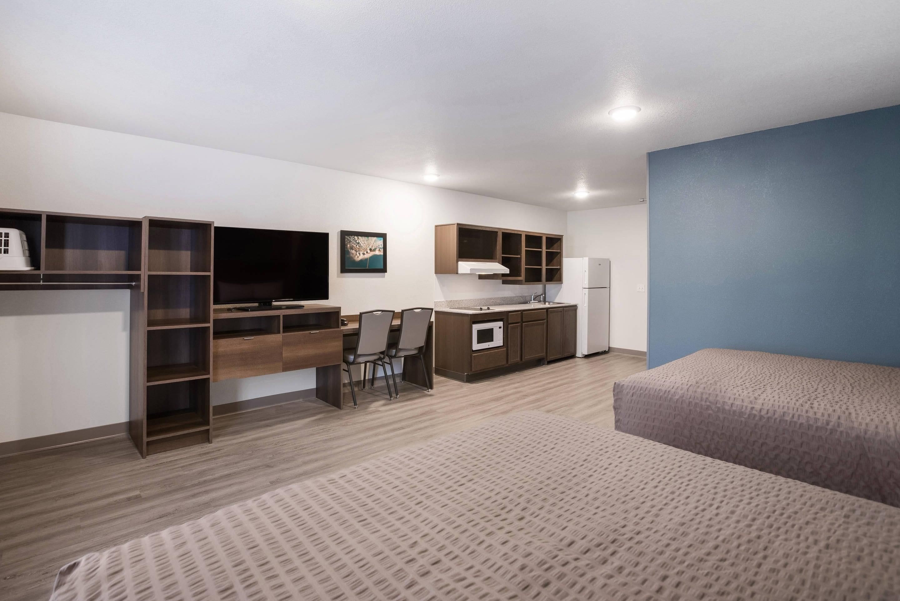 Una habitación pequeña con kitchenette, cama y escritorio.