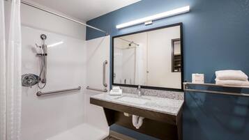 Un bany amb plat de dutxa, un lavabo amb mirall i un esparrell per tovalloles.