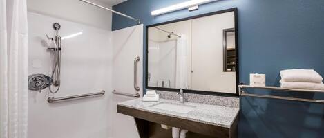 A bathroom with a walk-in shower, a sink with a mirror, and a towel rack.