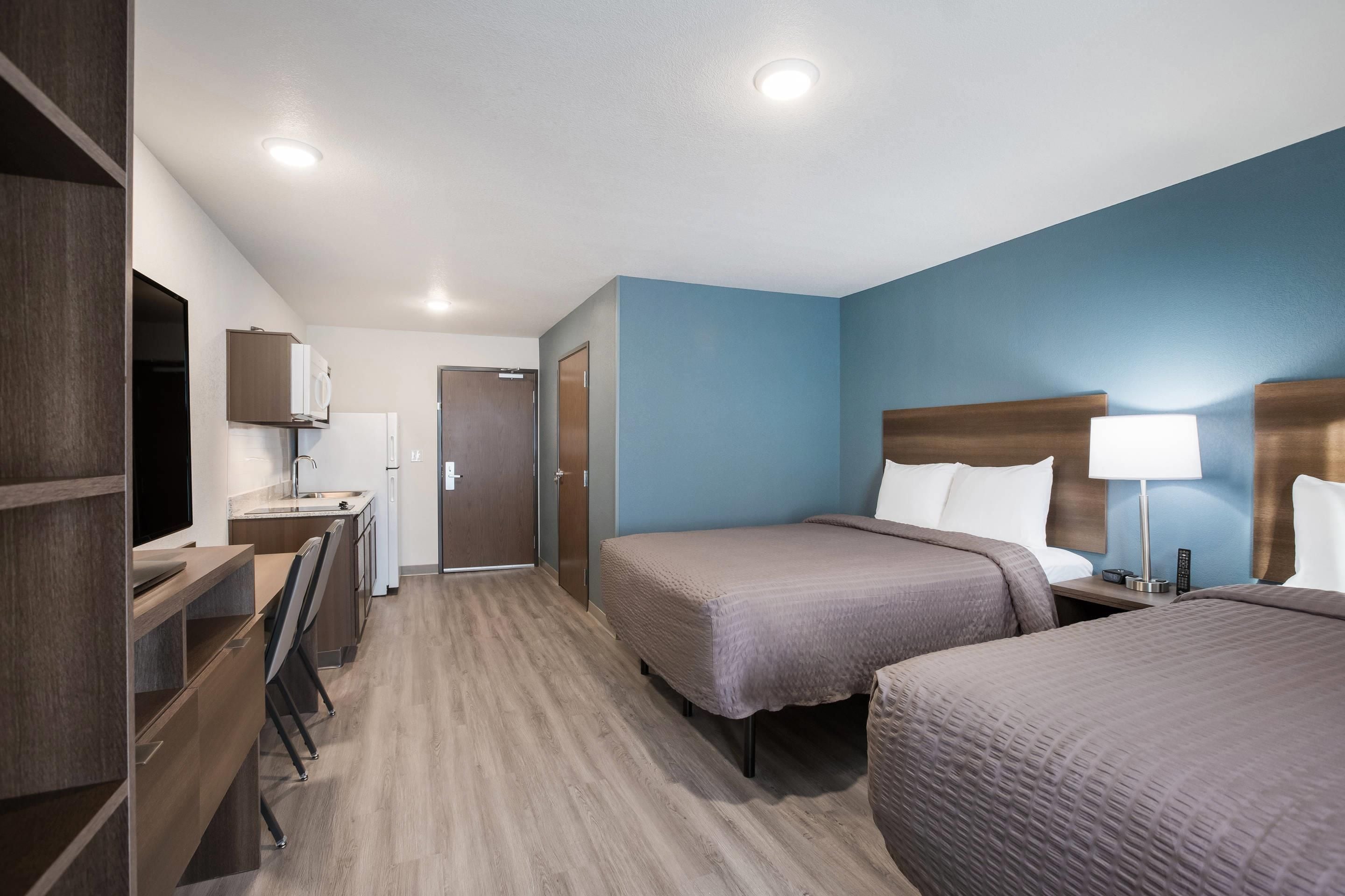 Une chambre d’hôtel équipée d’une kitchenette, d’un lit, d’un bureau et d’une salle de bain.