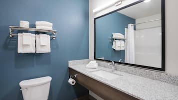 A bathroom with a toilet, a sink, a mirror, and a towel rack with folded towels.